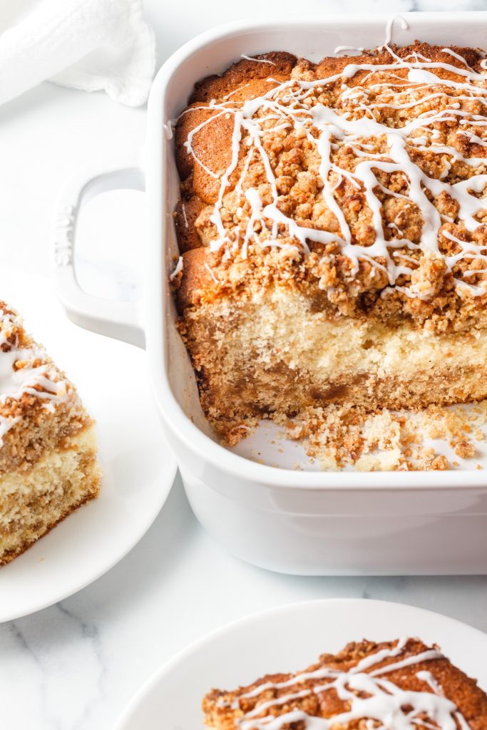 streusel cinnamon coffee cake in a white cake ceramic pan on a white neutral background