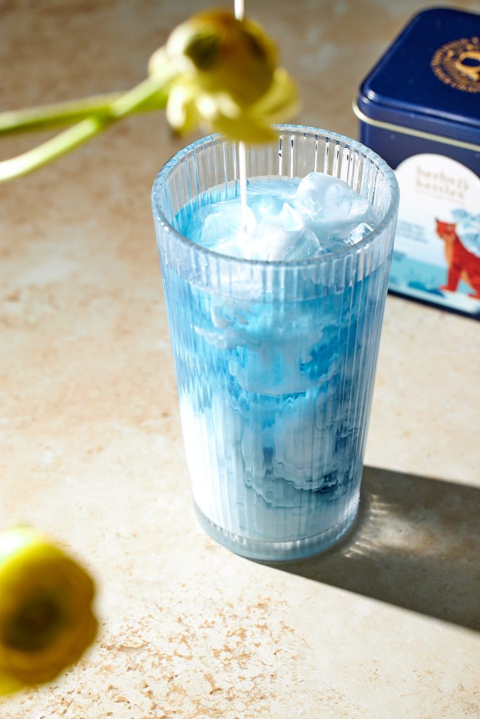 blue chai iced latte on a neutral background herbs and kettles