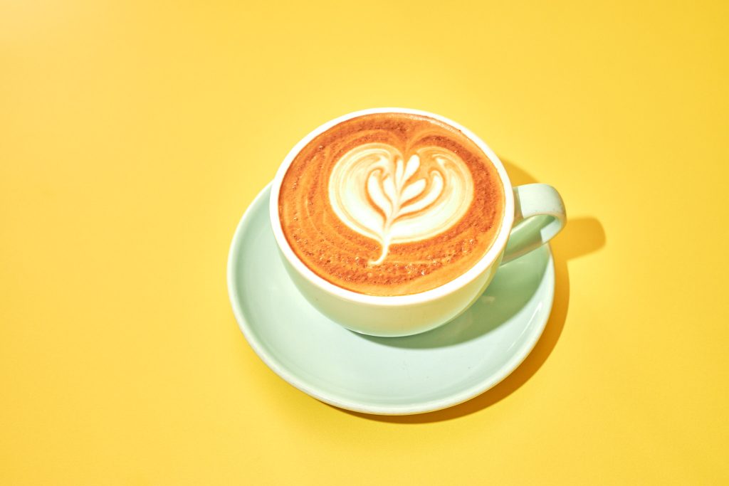latte art in a mint green cup on a yellow background