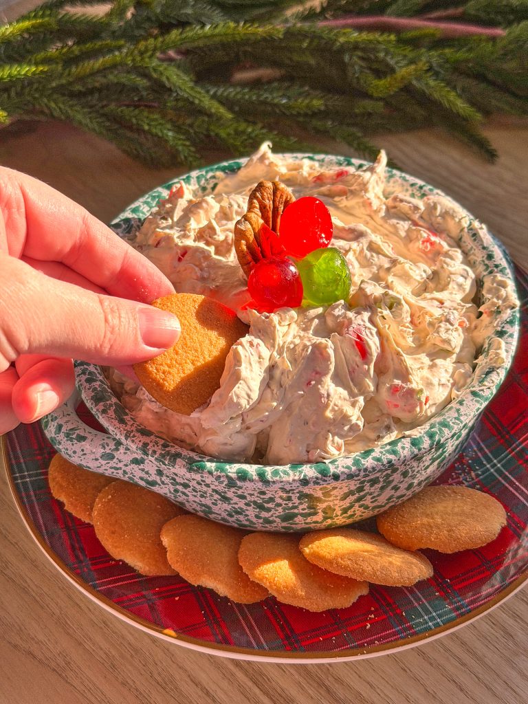 fruit cake dip with red and green cherries on top with nilla wafers on a tartan christmas plate on a neutral background