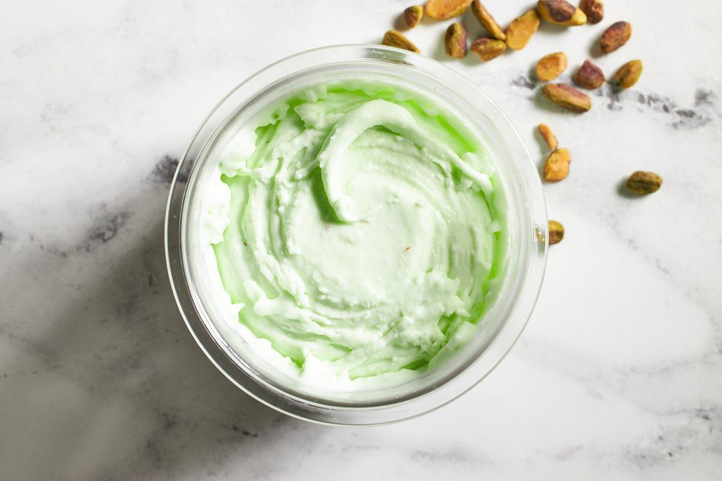 Ninja creami ice cream pistachio ice cream in a ninja creami container on a neutral background with pistachios