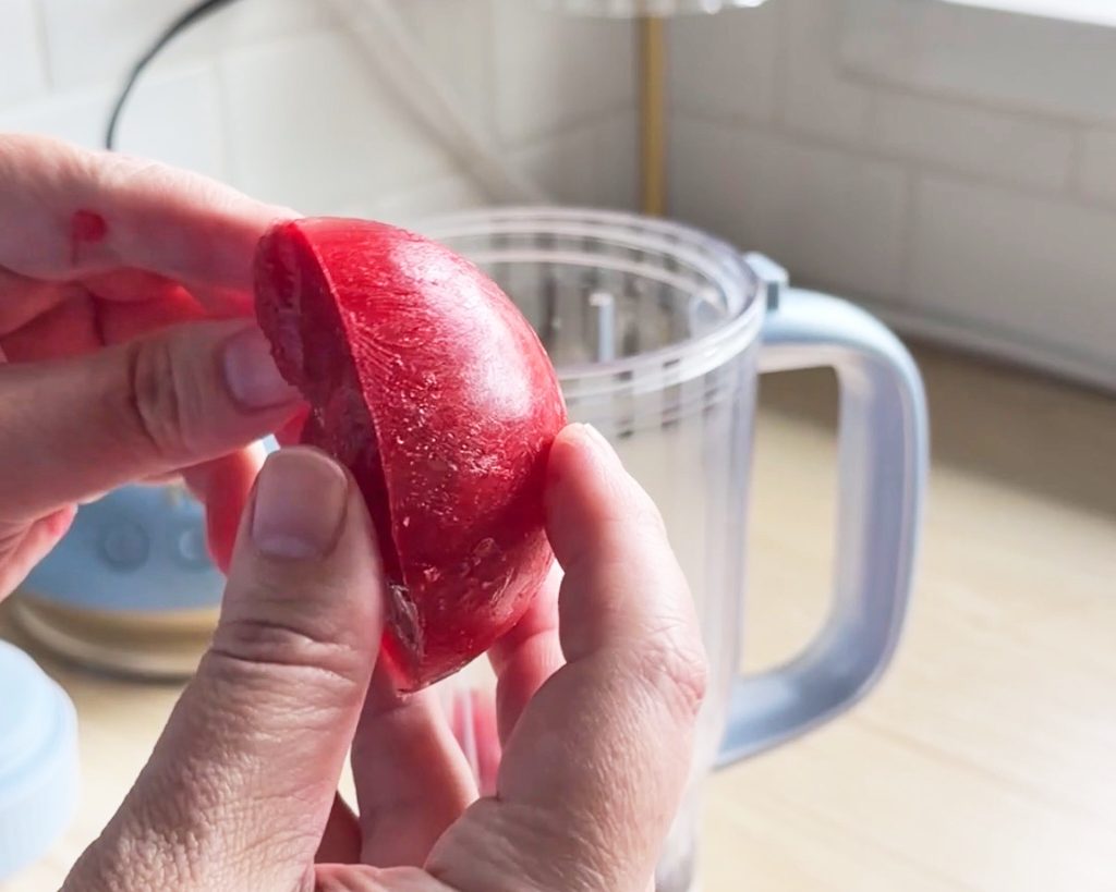 cooked and frozen strawberries held in a hand on a kitchen counter