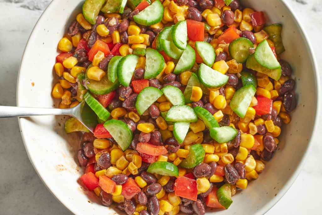 dense bean taco salad with black beans, corn, cucumbers, bell peppers, in a taco sauce,